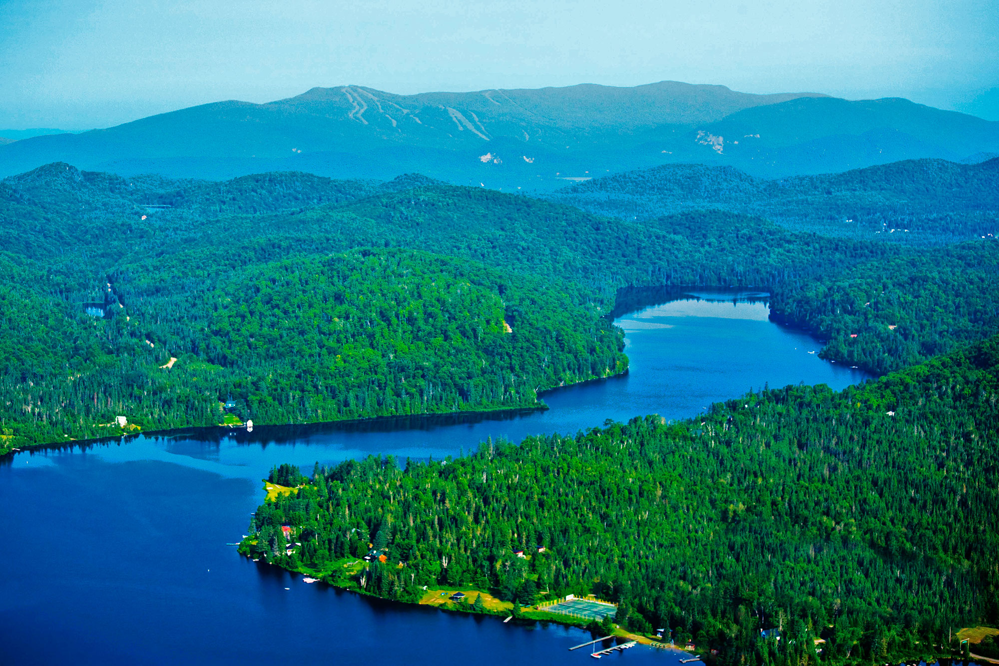 « À l'est du Canada, sur les rives d'un lac ou en pleine montagne, DTN propose des domaines privés, de 3 500 m² à 10 000 m². S'il existe un paradis pour les amoureux de grands espaces, d'air pur et de tranquillité, le parc national du Mont Tremblant s'en approche. Nous sommes ici au Québec, sur un vaste territoire de 1 500 km, offrant plus de 400 lacs, des rivières, des cascades et des centaines de kilomètres de sentiers qui en font un cadre absolument unique. C'est à 15 minutes à peine de Tremblant, le plus grand centre de villégiature du Québec et au coeur d'un espace sauvage et naturel grandiose, que s'inscrivent ces trois domaines privés viabilisés. Le premier, Domaine Nostalgia, est situé dans une superbe forêt d'érables et de sapins, et bénéficie d'un ensoleillement total. Il se compose de 70 terrains, d'environ 4000 m² chacun. Certains, nichés sur les hauteurs, bénéficient de vues dominantes sur les montagnes alentour et sur le Mont Tremblant. À vocation familiale, ce domaine bénéficie de nombreux aménagements : sentiers pédestres, jeux pour les enfants, espaces de loisirs, belvédère et accès aux lacs. Le second domaine, Domaine Secret Life, a la particularité d'offrir des vues panoramiques sur toute la vallée du Mont Tremblant et les grands lacs environnants. Il se caractérise également par ses grands espaces : tous les terrains font au minimum 8 000 m² et jusqu'à 15 000 m². Ultime privilège, les propriétaires ont accès aux lacs de pêche privés, situés en contrebas de la propriété. Enfin, Domaine Port d'Attache est un territoire de prestige, situé en bordure du grand Lac aux Quenouilles, lac navigable et accessible aux engins motorisés. Certains terrains limitrophes disposent d'un accès direct privé tandis que d'autres, plus en retrait, bénéficient d'un accès par une partie commune. Tous jouissent en tout cas de superbes vues sur le lac. L'AVIS DE FRANCK IACOMACCI Responsable des ventes pour la France de DTN Indicateur Bertrand : Quelle est la particularité de ces domaines? Franck Iacomacci : Ils répondent au rêve de ceux qui recherchent un refuge paradisiaque en pleine nature, au coeur de la forêt québécoise. Avec ces trois domaines, DTN, le plus grand propriétaire foncier de la région du Mont Tremblant, propose toute une gamme de terrains boisés, intimes, à proximité des services et de toutes les commodités au coeur des montagnes laurentiennes du Québec. Nous sommes situés à 12 km de Tremblant, à 1 h 20 de Montréal et à 1 h de l'aéroport de Montréal-Dorval. Tous nos domaines privés sont viabilisés et bénéficient de l'électricité. Nous réalisons la route principale du domaFranck Iacomacci, responsable des ventes pour la Franceine et les chemins d'accès aux propriétés et aménageons aussi des sentiers pédestres, jeux d'enfants, espaces de loisirs et accès aux lacs. Des entrées privées protègent l'intimité des résidences et nous leur associons toujours des matériaux nobles tels que le fer forgé la pierre ou le bois. I.B. : Combien coûte un terrain en pleine nature ? F.I. : Pour le Domaine NostaIgia, les prix varient entre 40 000 et 60 000 euros. Pour celui du Port D’Attache, ils vont de 87 000 à 206 000 euros. Un terrain viabilisé se vend en moyenne entre 10 et 15 euros le m², soit 42 000 euros TTC pour des parcelles de 4 000 m². À titre d'exemple, une maison clés en main, avec terrain, coûtera 175 000 euros, soit quatre à cinq fois moins qu'en France. D'ailleurs, 70 % de notre clientèle européenne est française, et les acquéreurs sont avant tout des promoteurs qui connaissent bien le marché. En outre, 50 % de nos ventes sont réalisées pour des placements, les domaines n’étant construits qu’à 30%. Cet acte de placement s’accompagne toujours d’une part de rêve : celui de construire sa cabane au Canada ! »